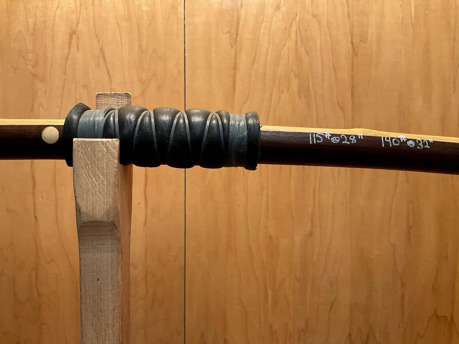 The deer skin and sinew handle wrap of the 115-pound bamboo-backed ipe warbow, its draw weights pencilled on the limb