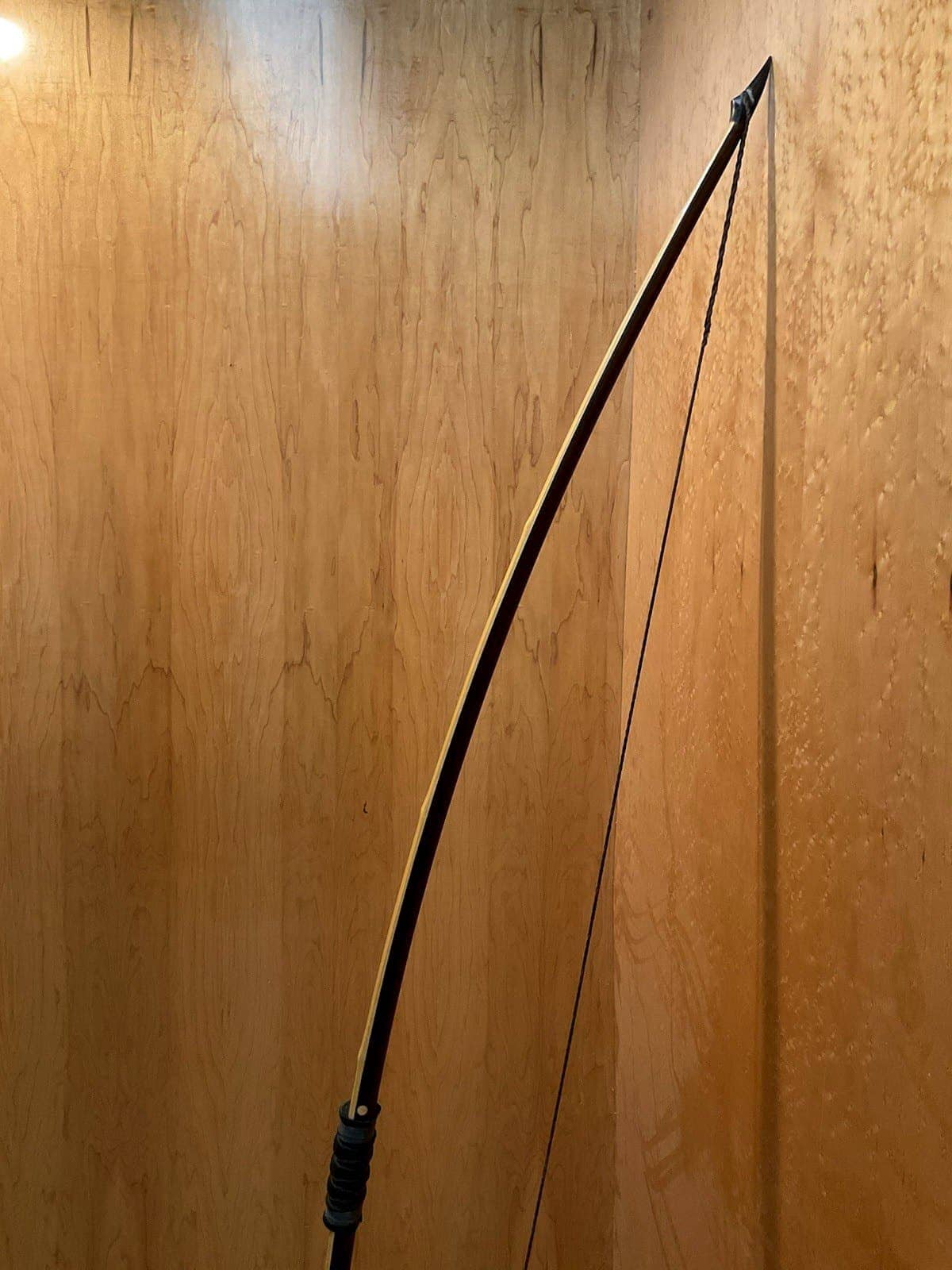 The curve of the 115-pound bamboo-backed ipe warbow, standing against the maple wall