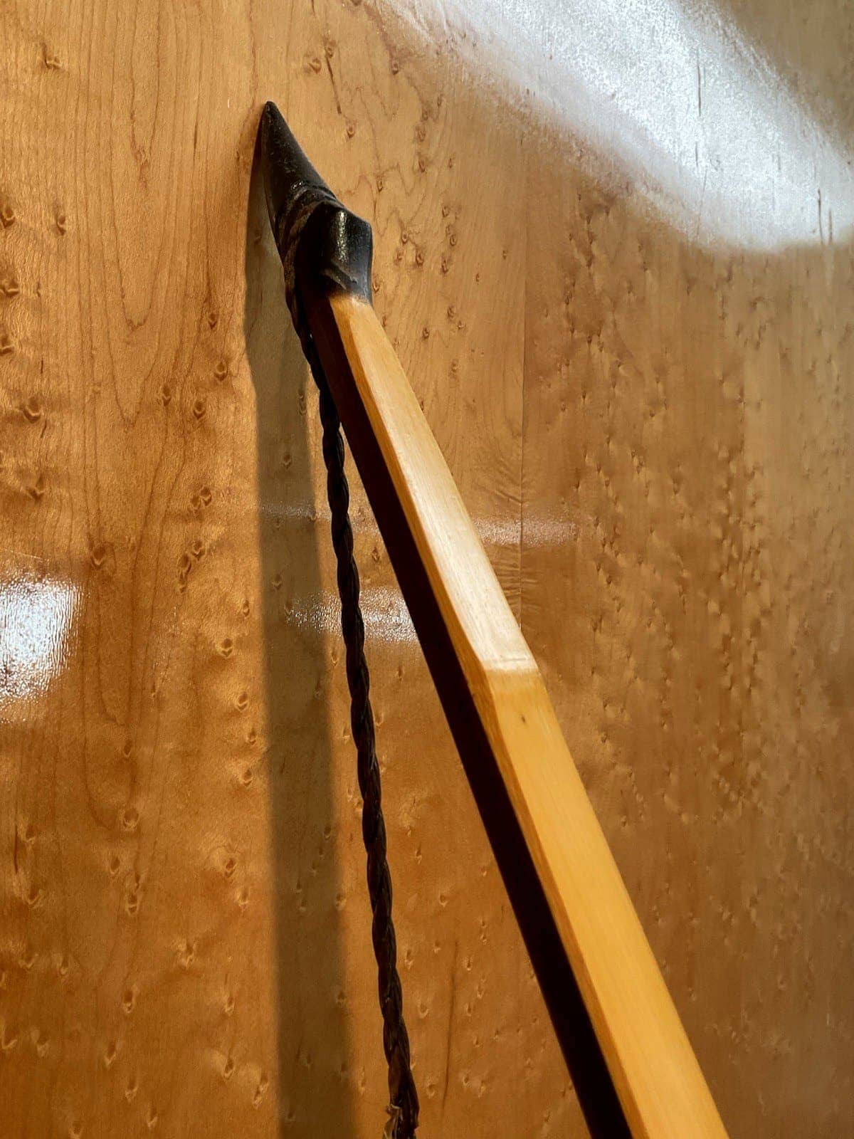 Close-up of the upper horn tip of the 115-pound bamboo-backed ipe warbow against the maple wall