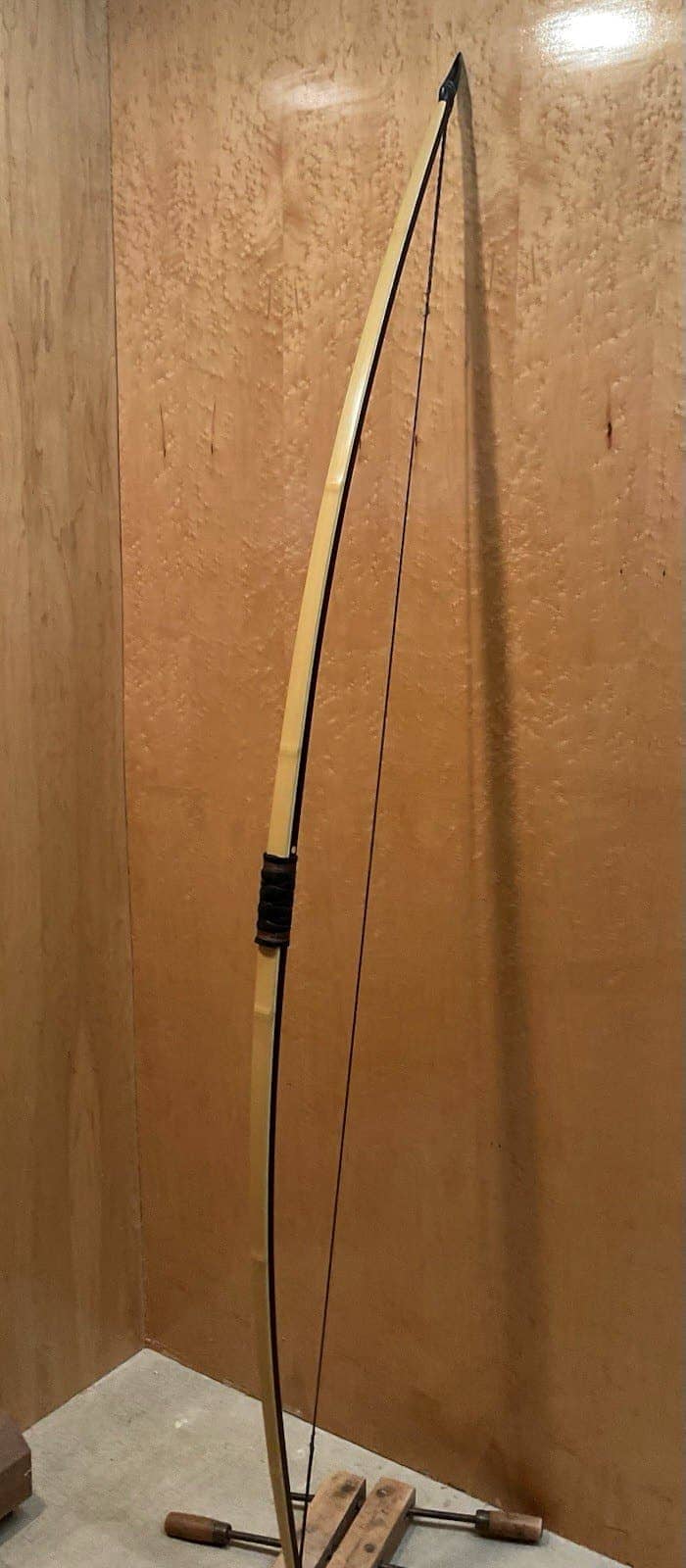 The 150-pound bamboo-backed ipe warbow, strung and standing full length against the maple wall