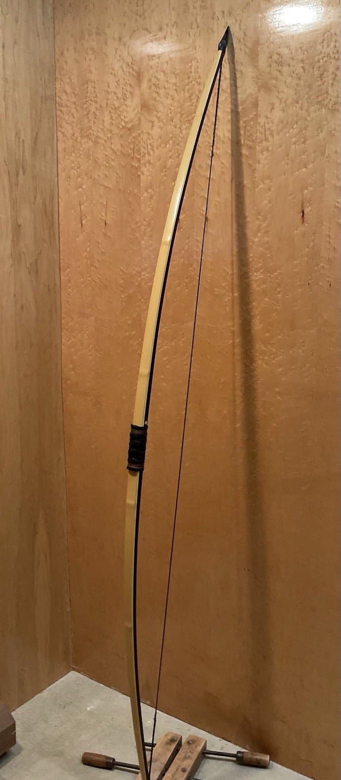 The 150-pound bamboo-backed ipe warbow, strung and standing full length against the maple wall