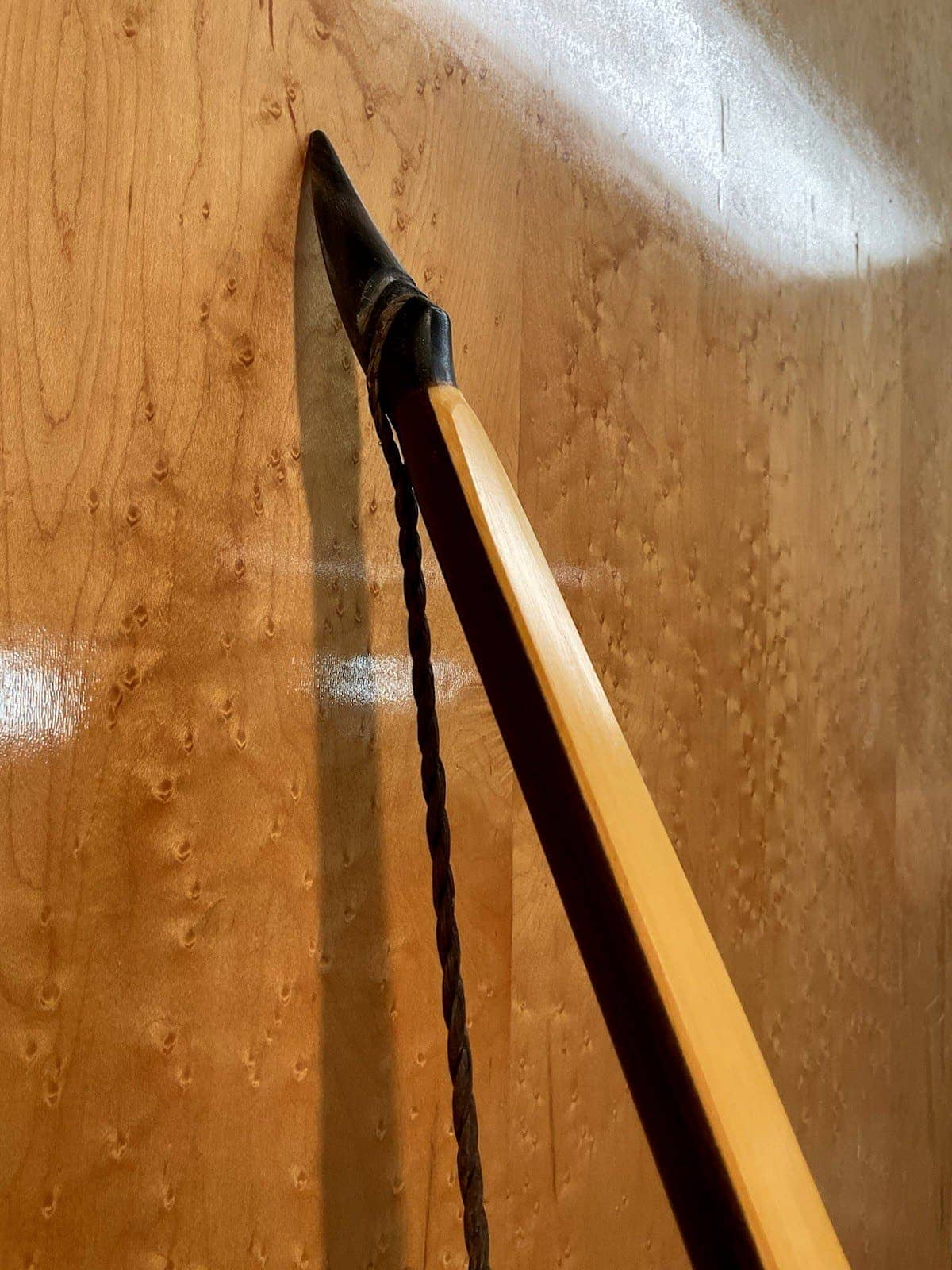 Close-up of the upper horn tip of the 150-pound bamboo-backed ipe warbow against the maple wall