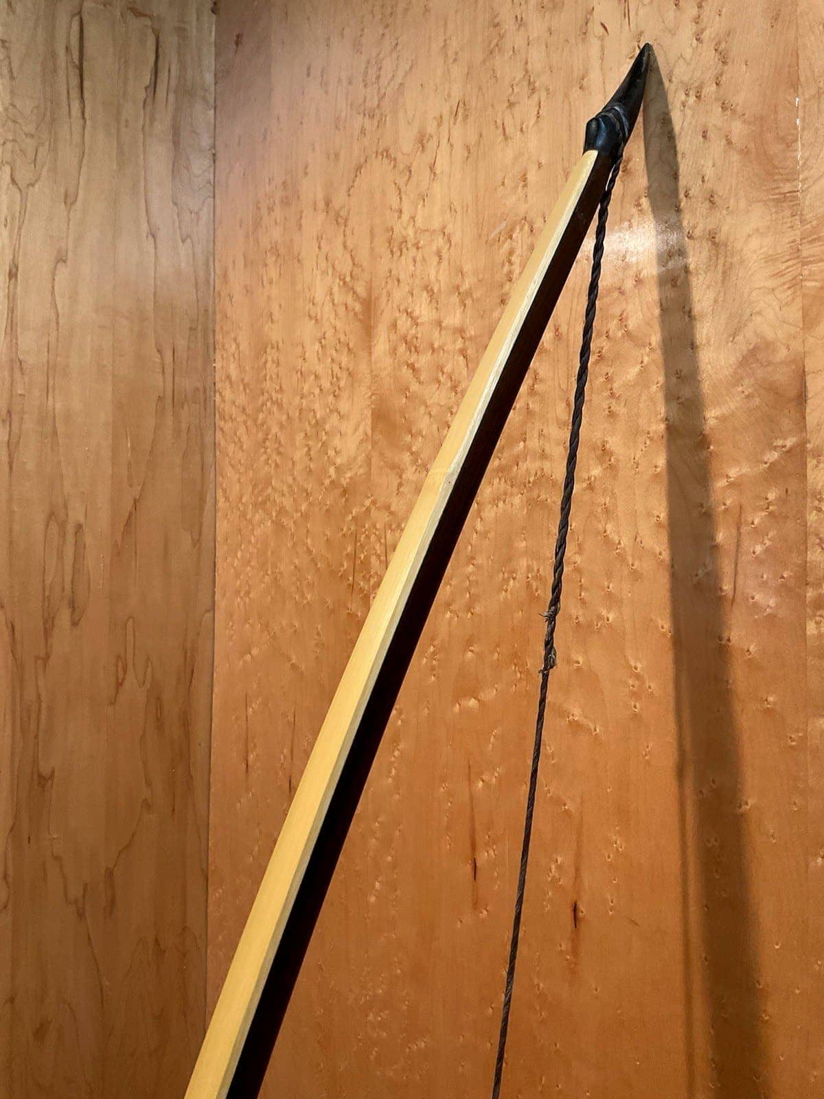 The upper limb of the 150-pound bamboo-backed ipe warbow, standing against the maple wall