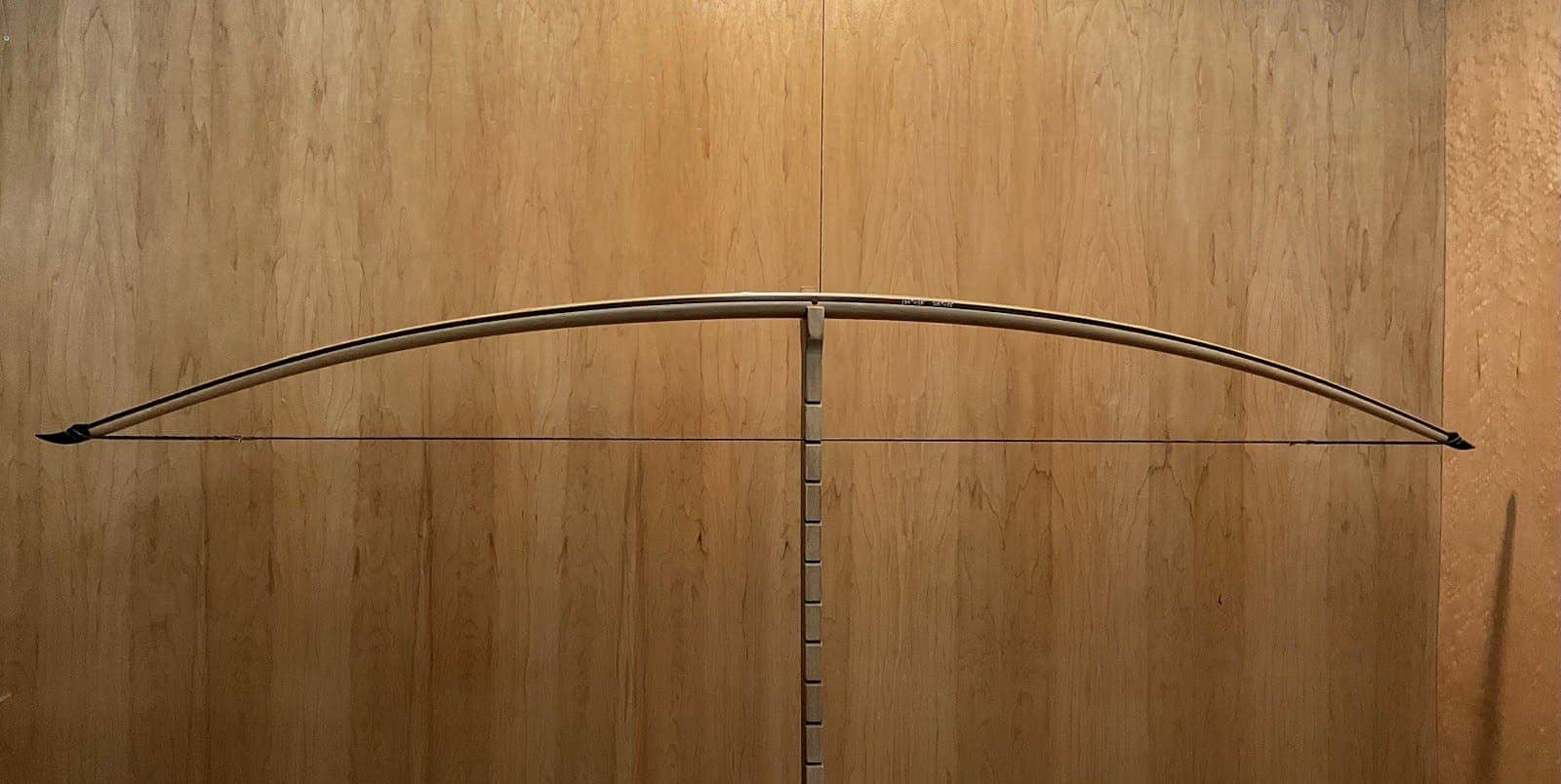 The 180-pound bamboo-backed tri-lam warbow, braced on Doug's tiller against the maple wall