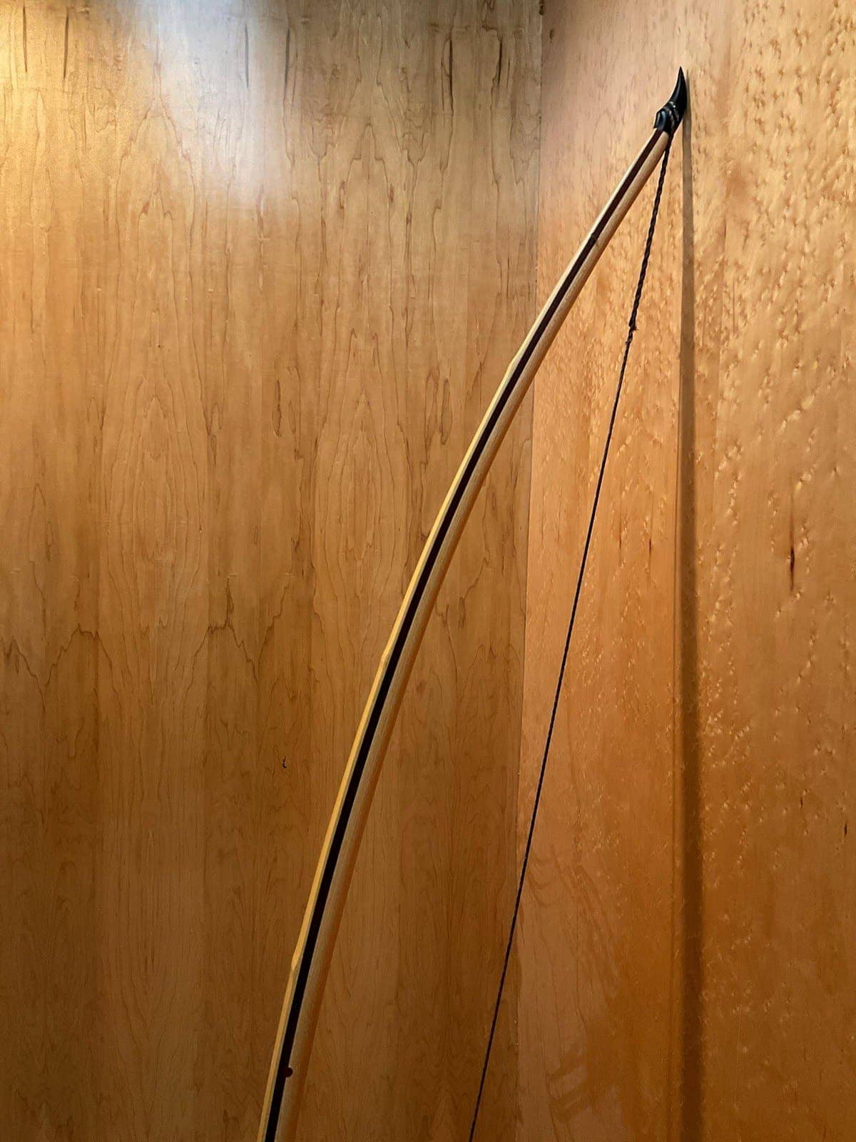 The curve of the 180-pound bamboo-backed tri-lam warbow, standing against the maple wall