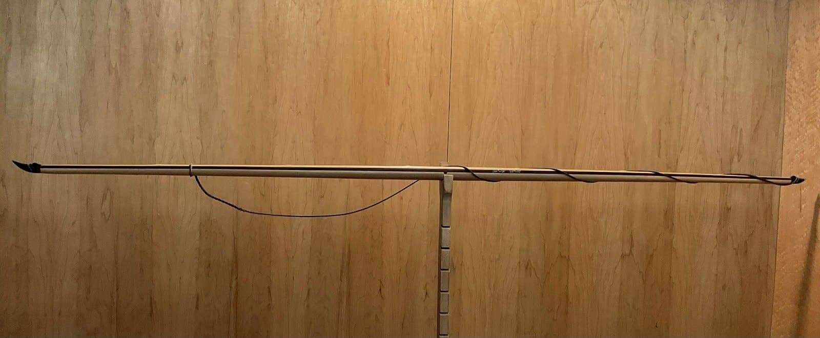 The 180-pound bamboo-backed tri-lam warbow, unstrung on the tiller, the string hanging slack