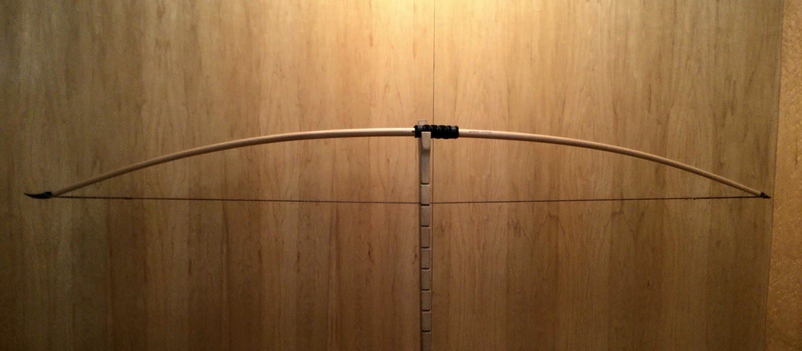 The 55-pound white hickory selfbow longbow, braced on Doug's tiller against the maple wall