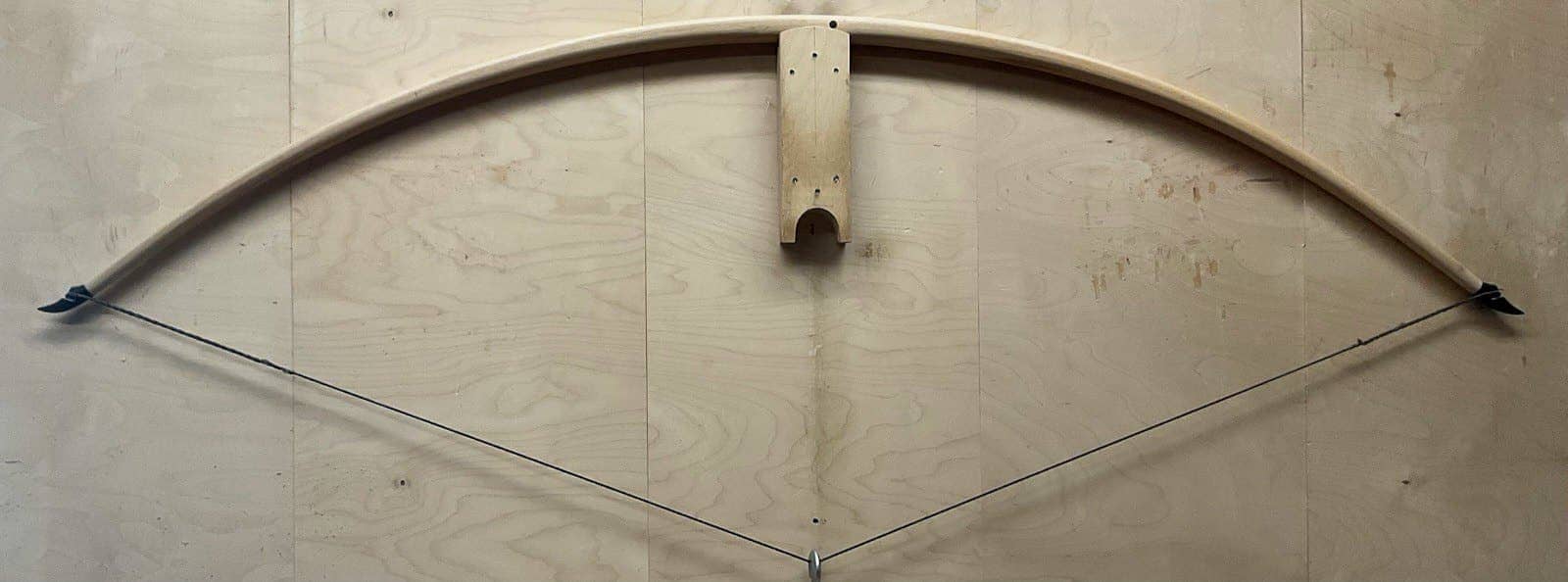 The 190-pound white hickory selfbow warbow, braced and hung on a wall peg
