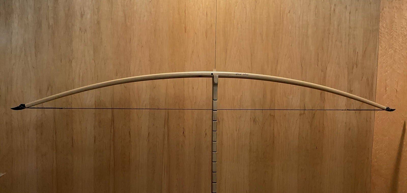 The 190-pound white hickory selfbow warbow, braced on Doug's tiller against the maple wall