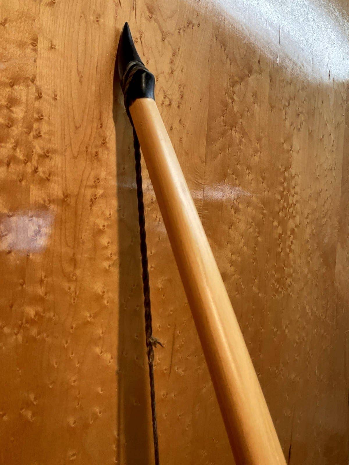Close-up of the upper horn tip of the 190-pound white hickory selfbow warbow against the maple wall