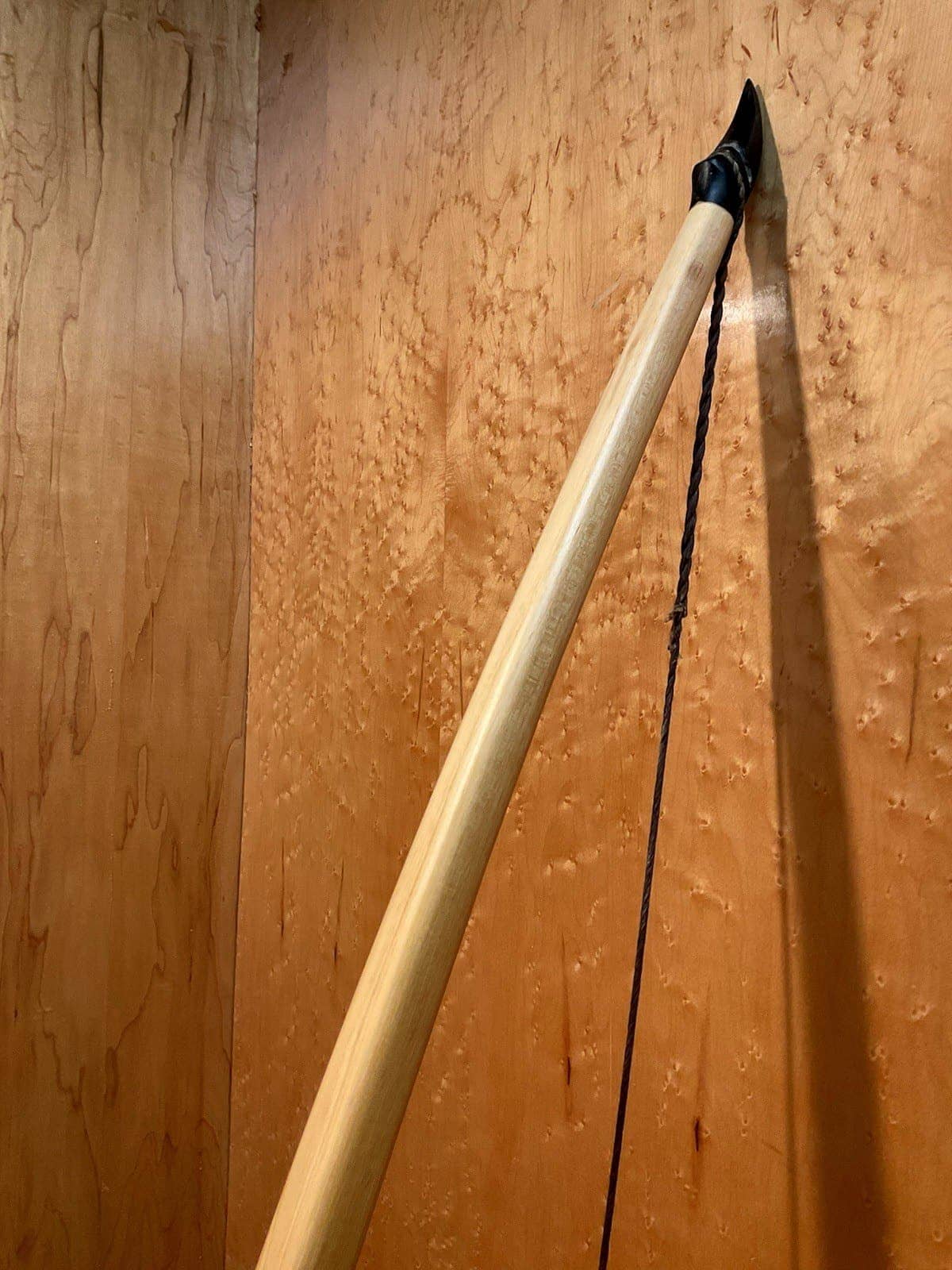 The upper limb and horn of the 190-pound white hickory selfbow warbow, standing against the maple wall