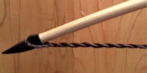 The lower buffalo horn nock of a pale longbow with its twisted string
