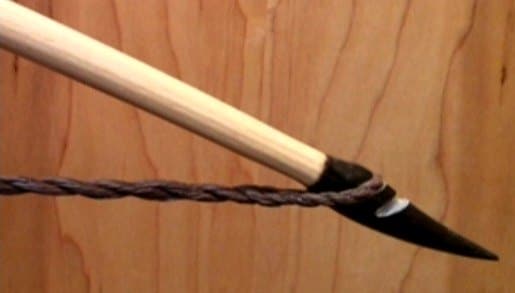 The upper buffalo horn nock of a pale longbow with its twisted string